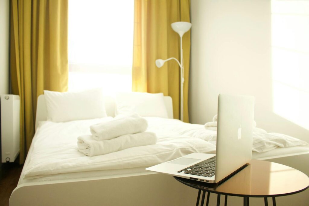 Macbook Air on Brown Wooden Table Near Bed