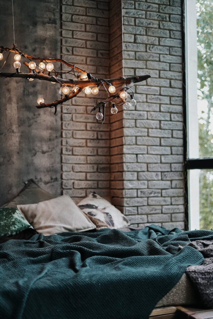 Glowing lights on branch in air over bed in room