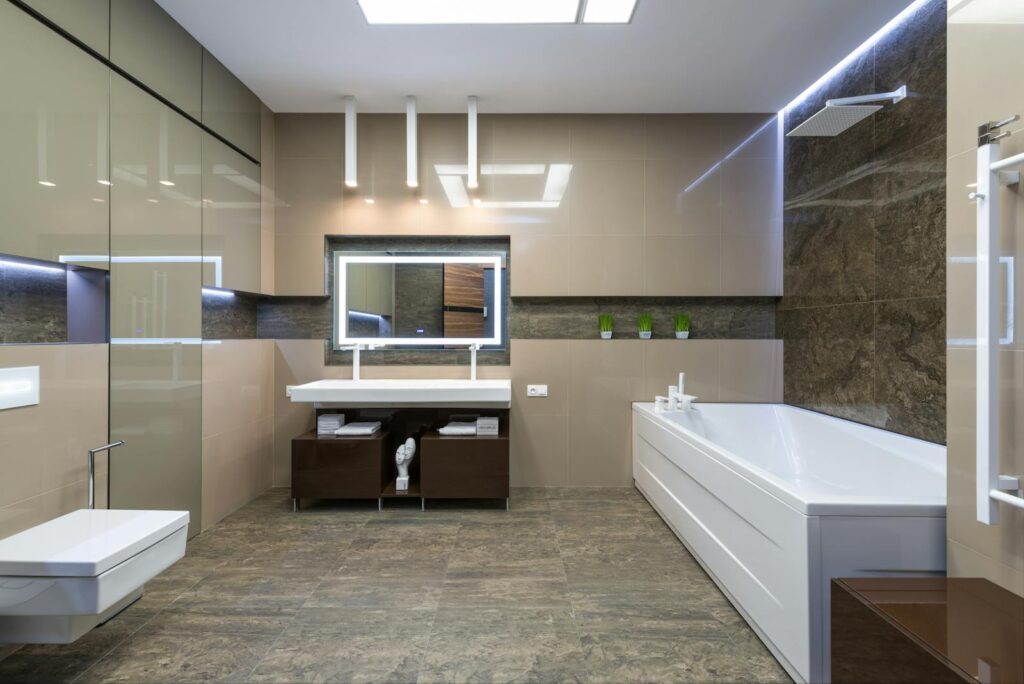 White bath placed near sink with mirror in light spacious bathroom with sink and toilet in modern bathroom with apartment